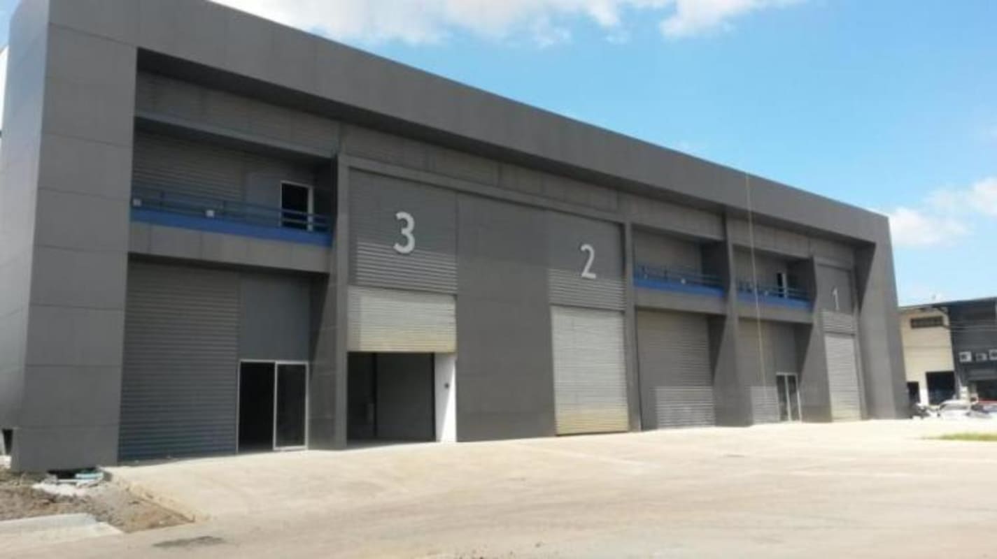 Modern facade of industrial warehouse units with access driveway and roller doors Panama Distribution Center Juan Díaz