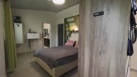 Spacious bedroom with built-in shelving, ensuite bathroom, neutral decor and garden view in luxury El Valle home