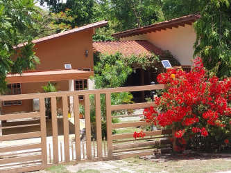 Rustic bungalow with red tile roof solar panels lush garden Los Lirios Panama