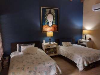 Bedroom with twin beds blue accent wall nightstands paintings Los Lirios Panama