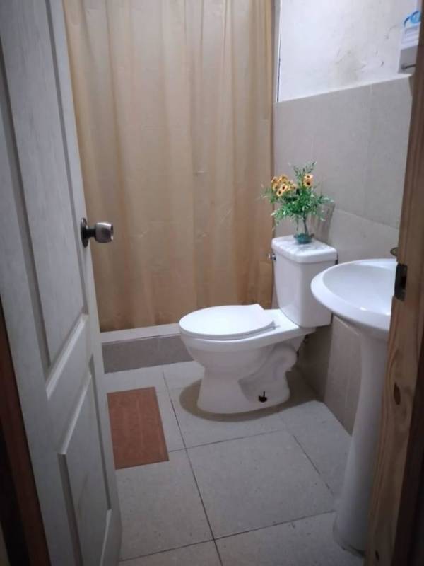 Compact bathroom with pedestal sink, toilet, and beige tiles in Las Mañanitas Panama City