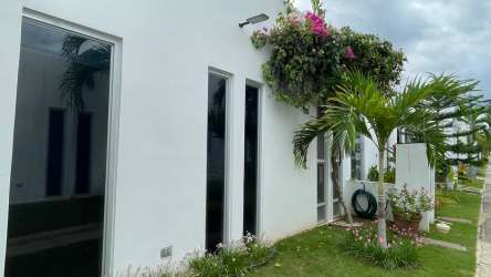 Minimalist facade with tall windows, landscaped garden, palm trees in Ibiza Beach Residences Río Hato Panama