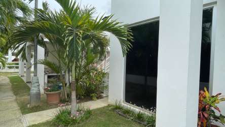 White modern villa exterior with palm trees and garden in PH Ibiza Beach Residences Río Hato Panama