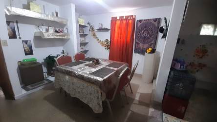Dining area with eclectic decor, wall shelves and red curtains Los Rosales house Arraiján Panama
