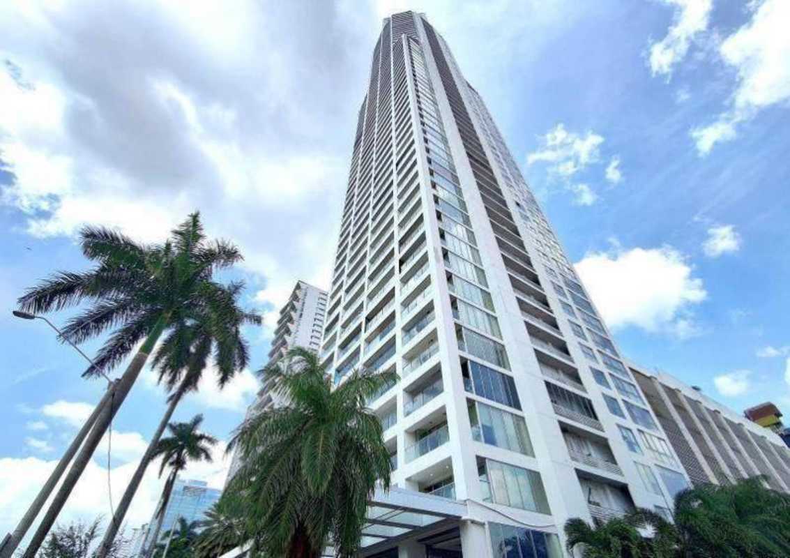 Tall modern luxury high-rise condominium with glass balconies and palm trees on Avenida Balboa Panama