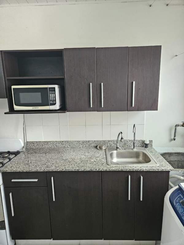 Bedroom with metal bed frame, wall mounted TV, ceiling fan, window blinds PH Parques del Este Panama City