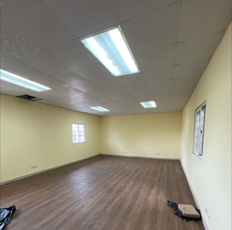 Empty office space with yellow walls, laminate floors and windows inside warehouse for lease Chanis Panama