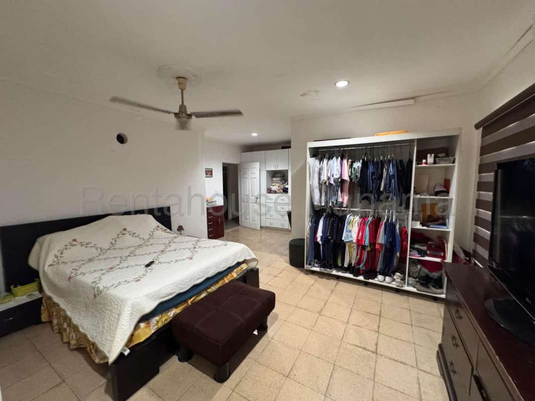 Bedroom with tile floors, built-in closet, ceiling fan, and large window in Villa Lucre Panama