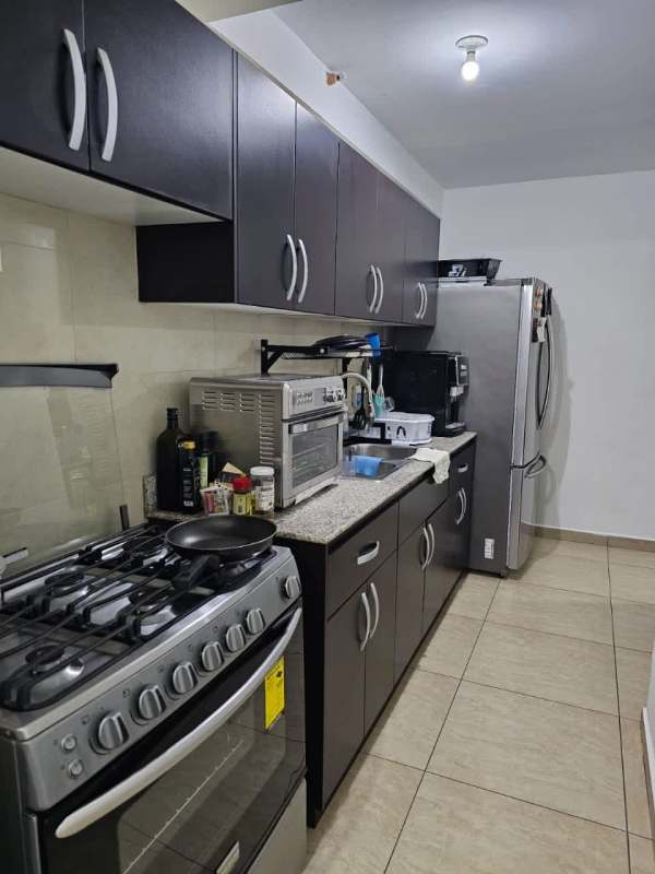 Kitchen with granite countertops, dark wood cabinets, stainless appliances in Vista Park Tower Carrasquilla Panama