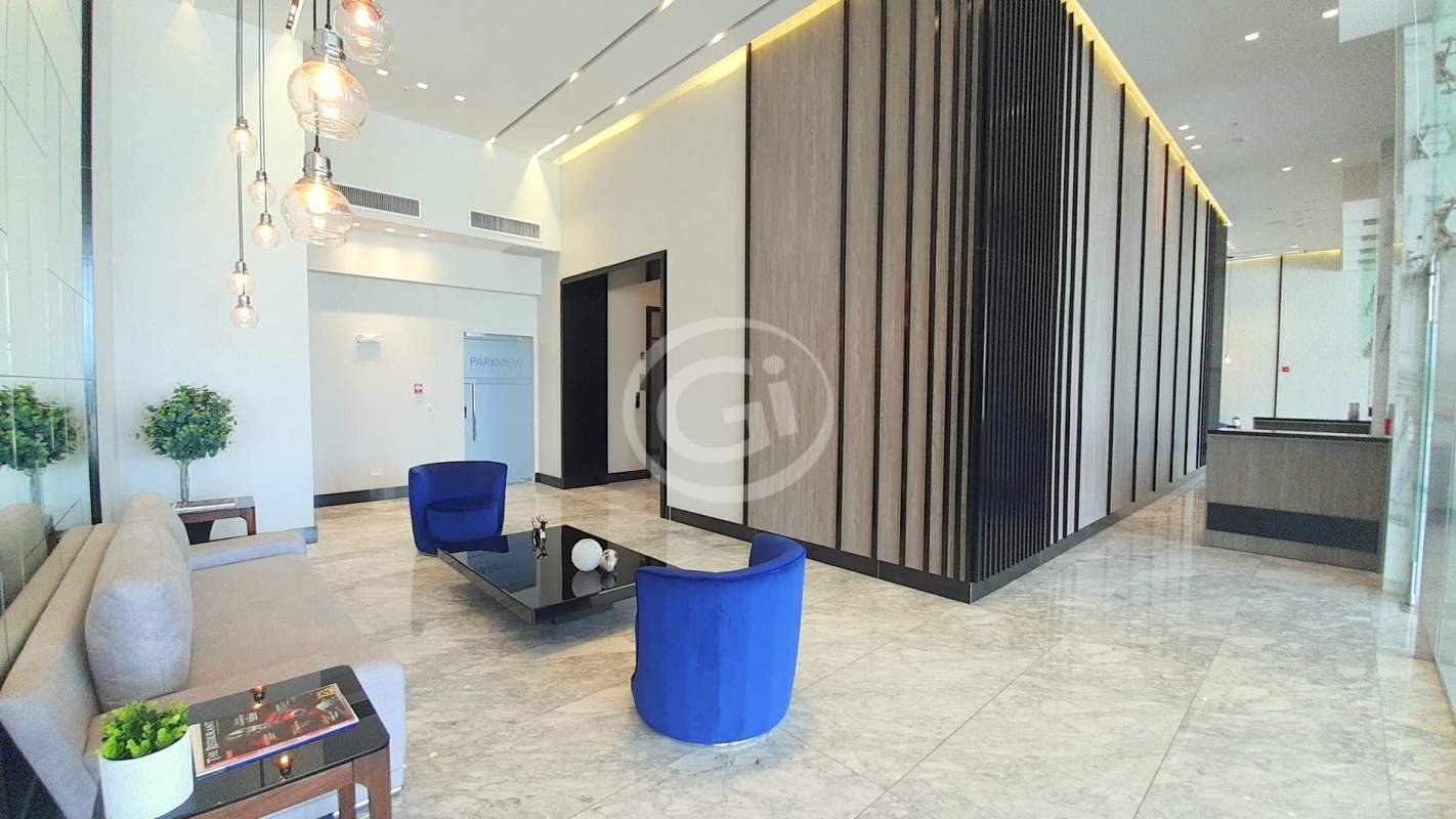 Modern lobby with marble floors, blue accent chairs, and double height ceiling at PH Park View Costa del Este
