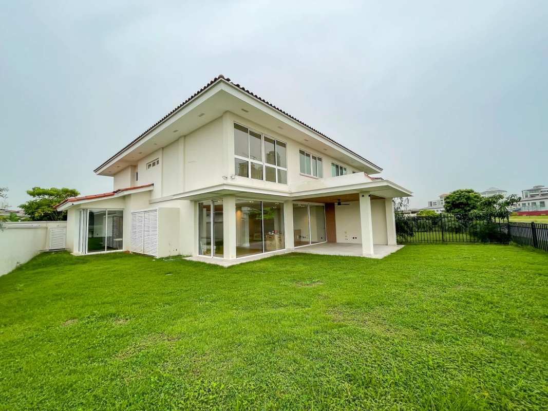 Open space living room with wood floors, modern staircase, and large windows in Santa María The Grove house Panama