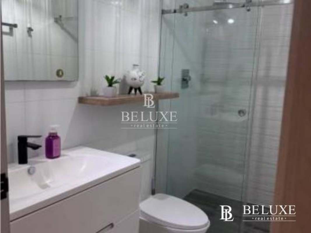 Sleek bathroom with glass shower, wood shelf, modern vanity in Nautica Tower Coco del Mar