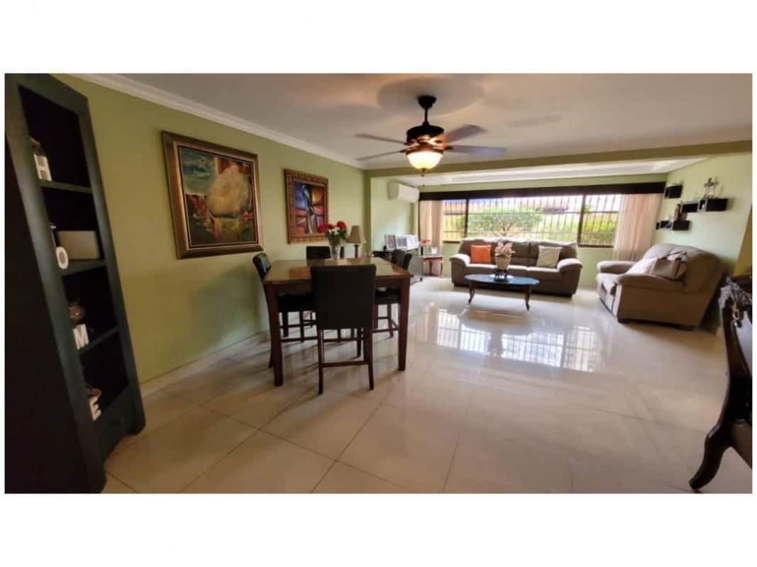 Large living and dining area with windows, tile floors, and ceiling fan in Altos del Golf home