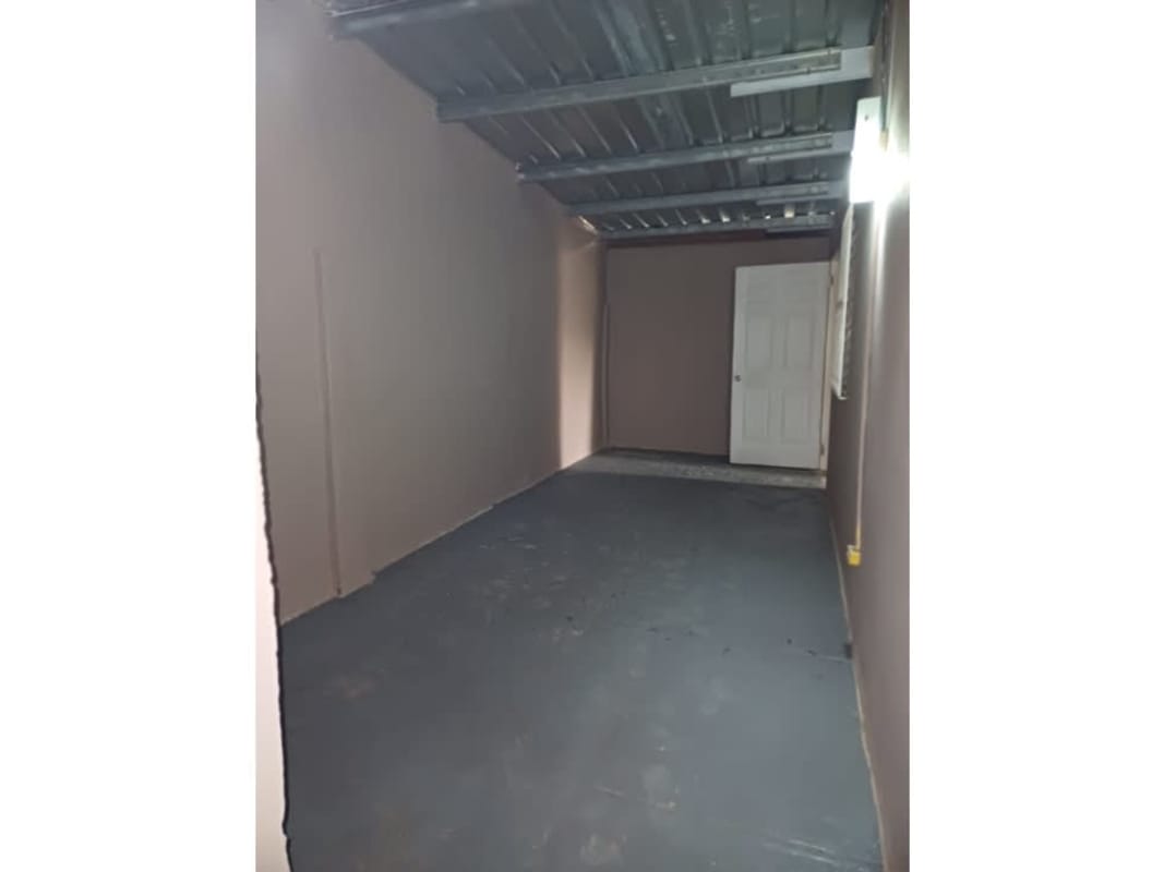 Covered garage area with concrete floor and storage Don Bosco house for sale