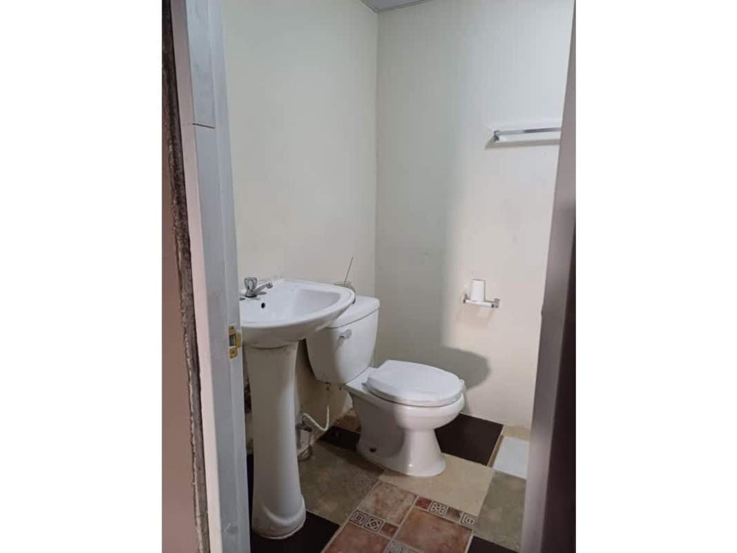 Bathroom with pedestal sink, toilet, and tiled walls Don Bosco house sale Panama