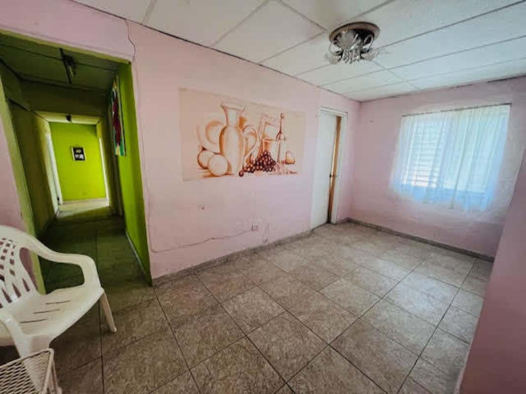 Covered front porch with yellow walls, arched entry and garden Betania Panama