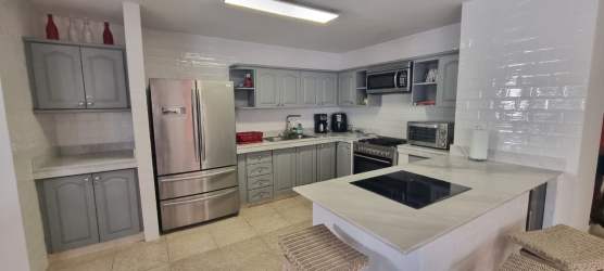 Modern kitchen with gray cabinetry, stainless appliances, electric cooktop, peninsula island and bar seating in Playa Blanca villa Panama