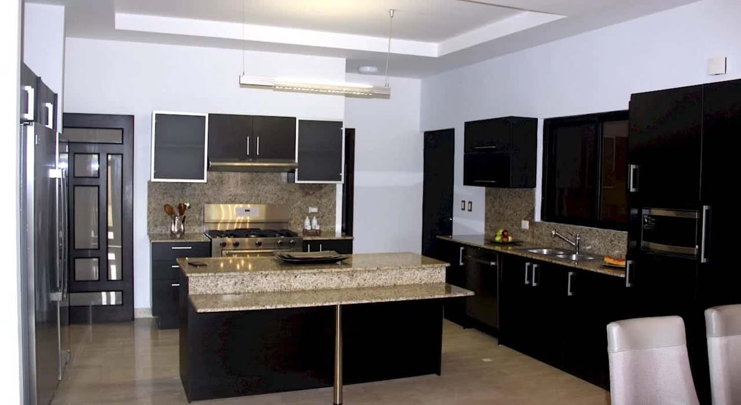 Modern kitchen with black cabinetry, granite countertops, stainless appliances in Sunset Coast Costa Sur Panama