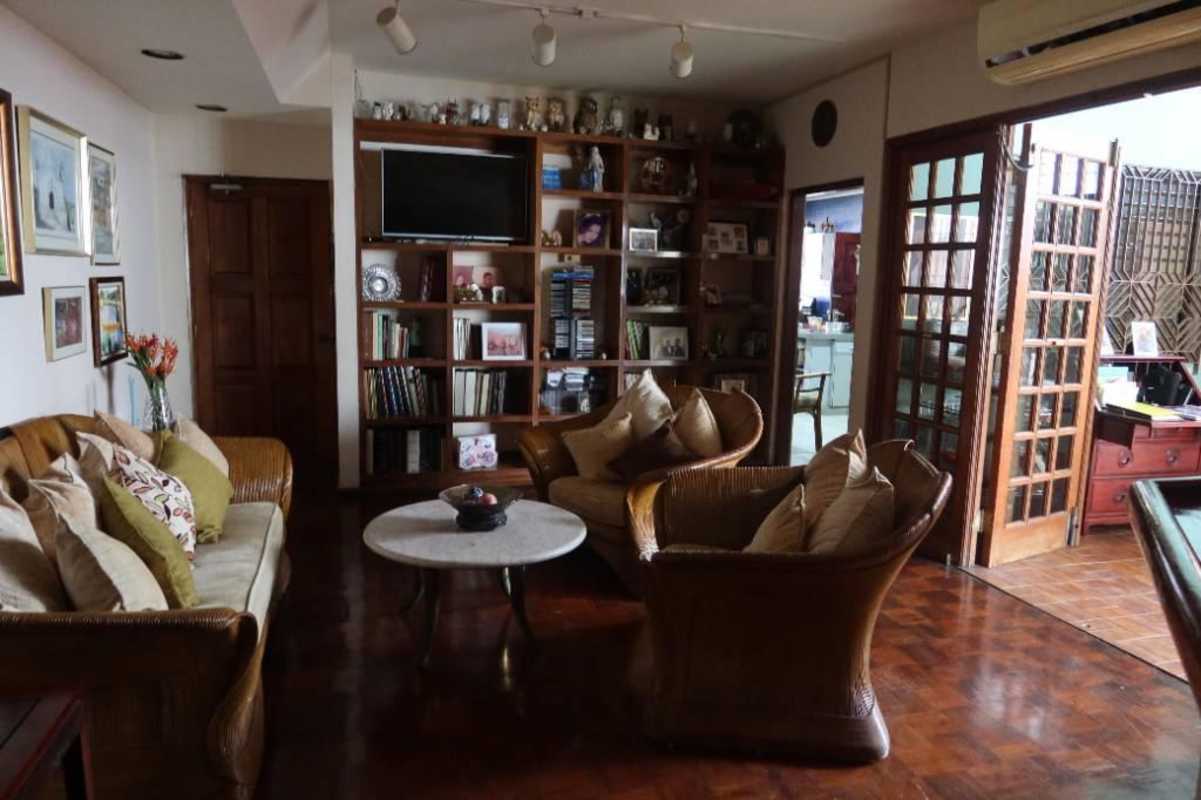 Traditional living room with wicker sofas, built-in bookshelf, and TV in San Miguelito home Panama