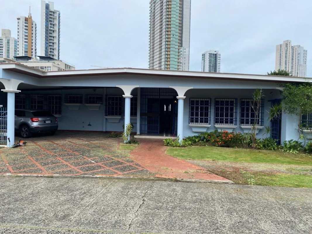 Residential home entrance with metal security gate, blue facade, wooden door in Pedregal Panama