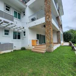 Multi-story white villa with balconies, stone columns, patio and green lawn PH Punta Barco Village Panama