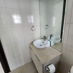 Bathroom with vessel sink on stone countertop, large mirror and tiled walls Punta Barco Village Panama