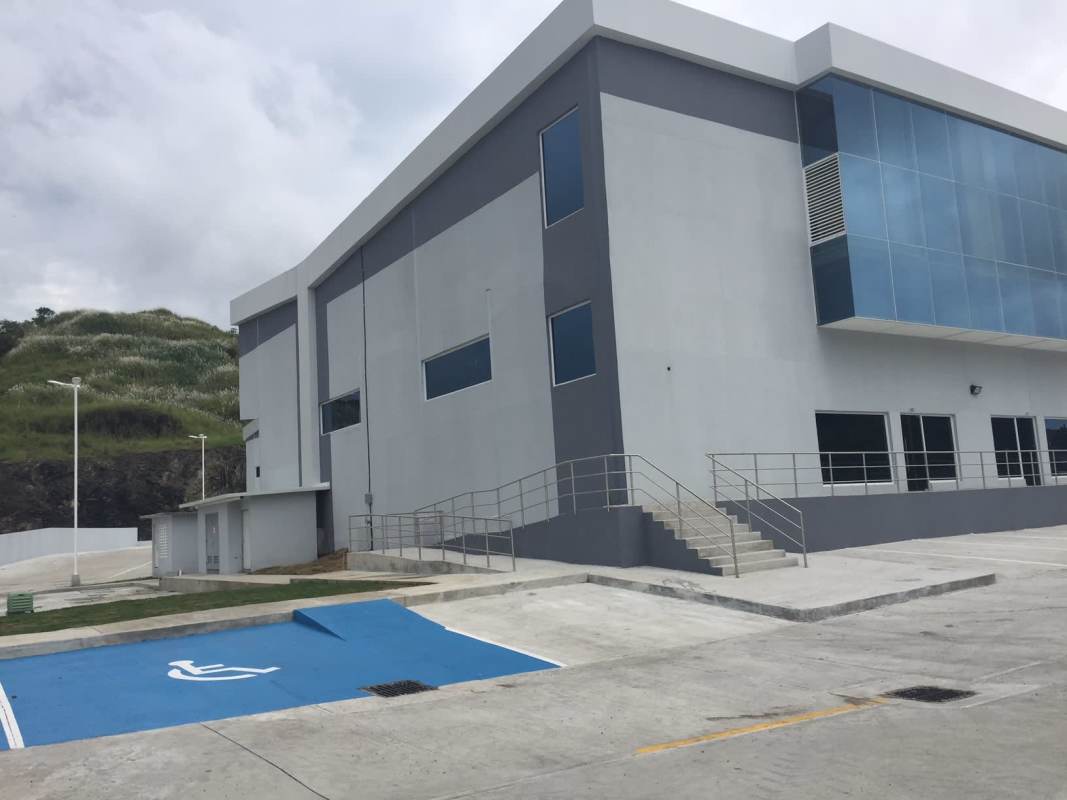 Warehouse exterior with glass facade section, accessible stairs and parking at Parque Centenario Panama