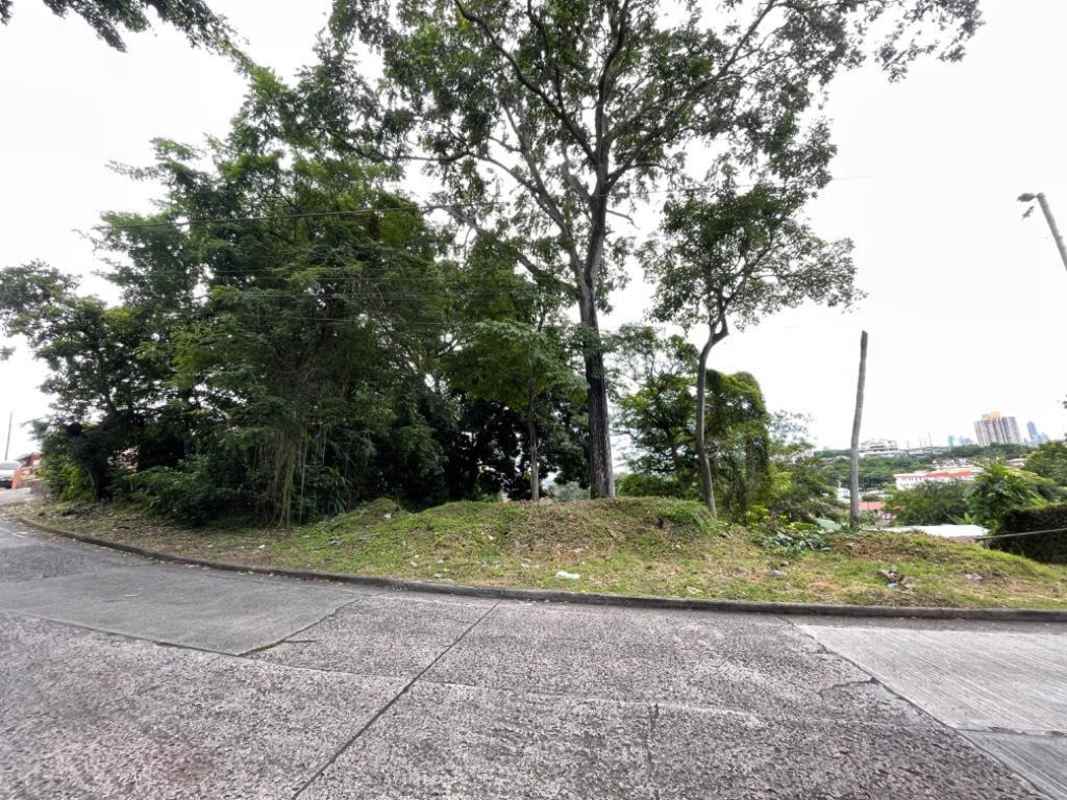 Sloped vacant land with mature trees and paved road access in Paraiso neighborhood Panama City
