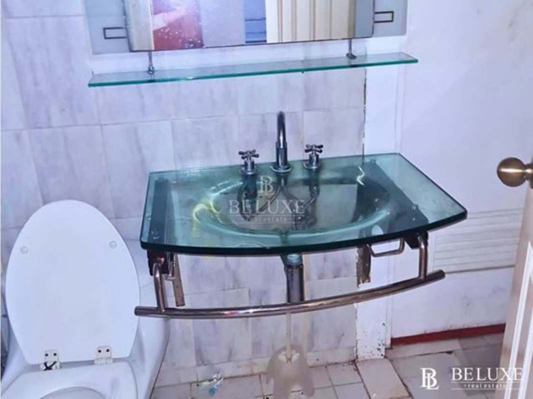 Bathroom interior with glass sink, wall mirror, tiled walls and white toilet in PH El Cangrejo Business Center Panama City
