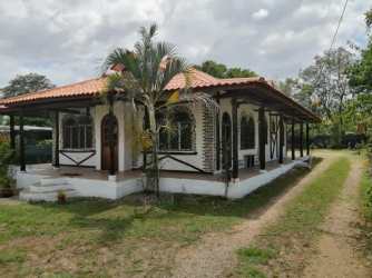 Home entrance with arch door, porch, garden landscaping and palm trees in Chigore Penonomé