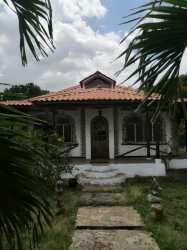 Rustic covered parking area with fenced backyard and lush greenery in Chigore Penonomé