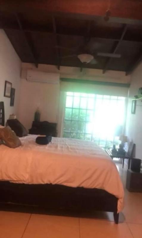 Bedroom with wooden beams, large window garden views in Panama rental home