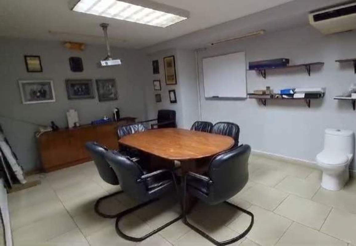 Office conference room with wooden table, black chairs, projector and whiteboard in Santa Elena commercial building