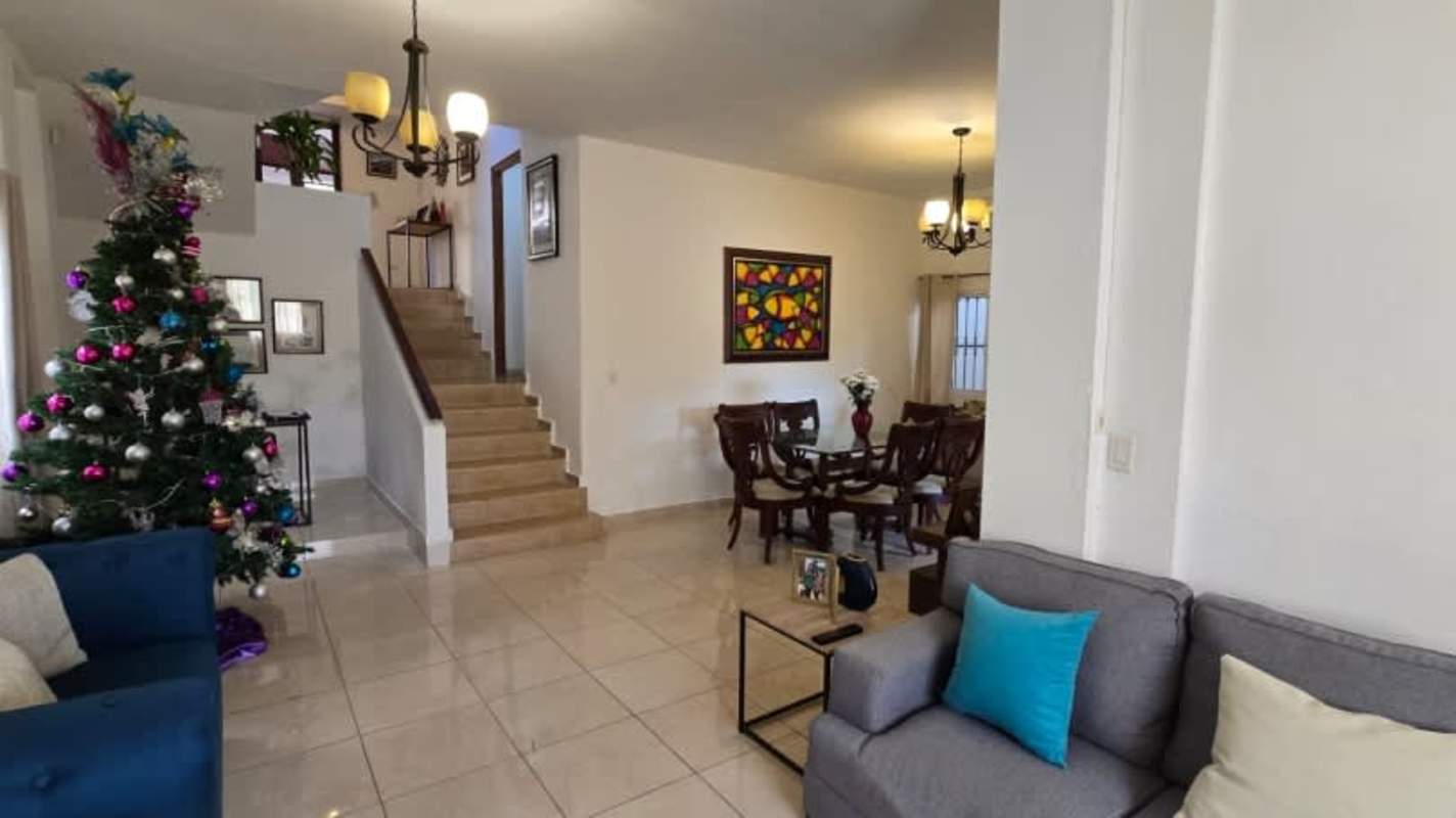 Bright dining room with glass table, wooden chairs, staircase, and chandelier in Panama