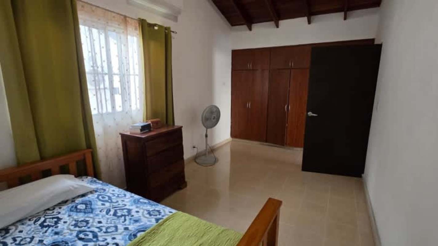 Simple bedroom with exposed wood beams ceiling, tiled floors, and closet in Panama