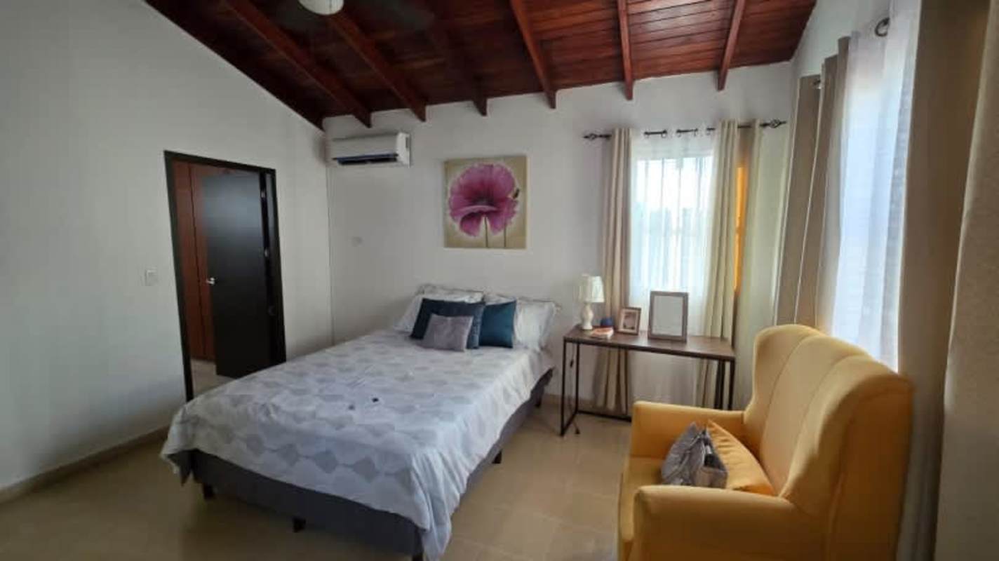 Cozy bedroom with vaulted wooden ceiling, bed, armchair and large windows Panama