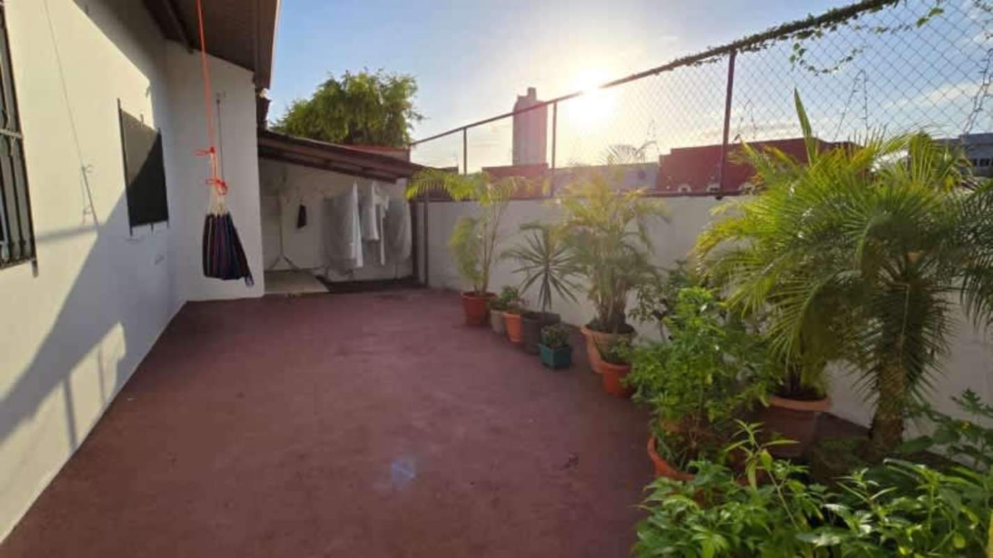 Outdoor terrace with potted plants, hammock, chain-link fence city view Panama
