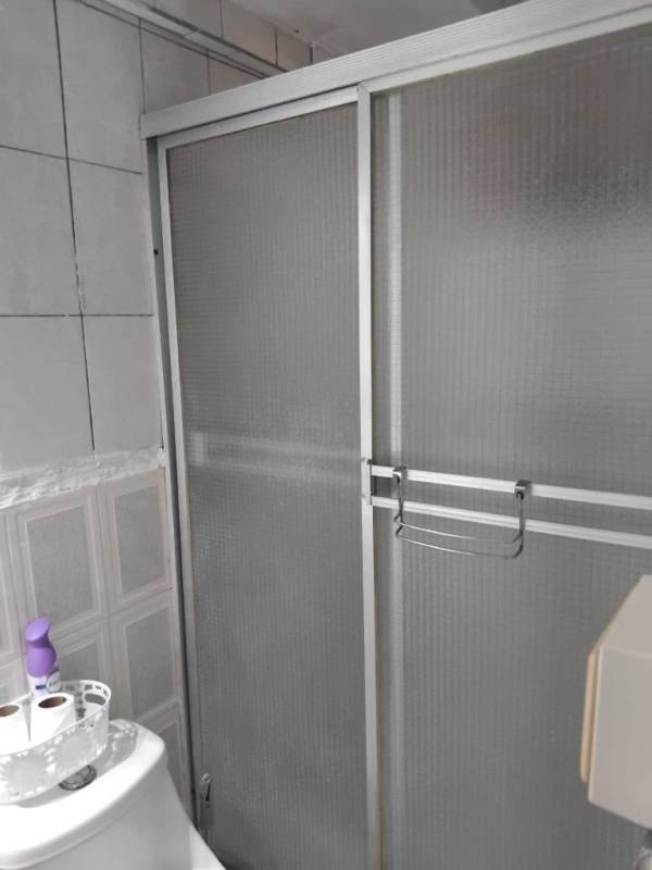 Bathroom featuring frosted glass shower door, toilet, tiled walls rental at Villa de las Fuentes Panama