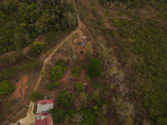 Bird's eye view rustic country house red roof cleared plot dense vegetation Vista Bella Panama
