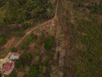 Aerial showing wooded property, dirt roads, red roof house in countryside Vista Bella Panama