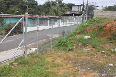 Gated corner lot along paved street, chain-linked fence boundary, residential zone