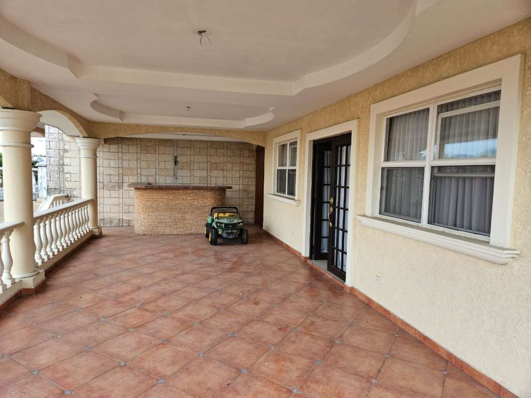Covered Mediterranean terrace with bar counter, arches, tile flooring in El Doral house Panama