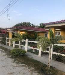 Coastal house with yellow walls, red tiled roof, garden, and fence in Playa Santa Clara Panama