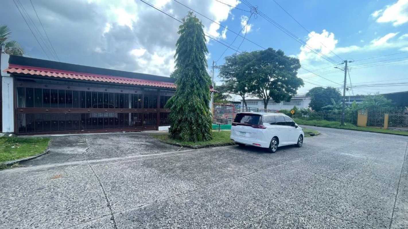 Corner lot view of suburban house with gated garage and paved driveway in Monte Oscuro Pueblo Nuevo Panama