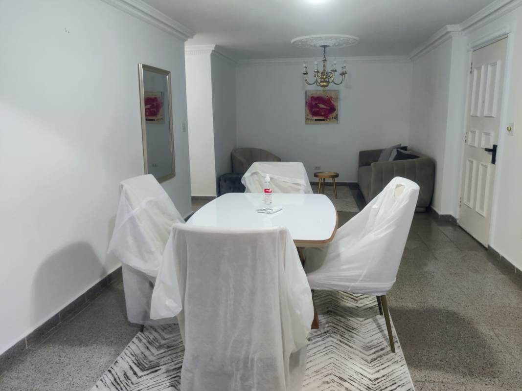 Dining and living area with chandelier, wall mirror, white walls, tile flooring in PH Juan Pablo Segundo Panama