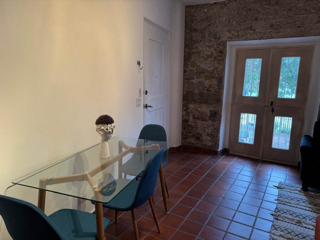 Dining area with glass table, blue chairs, stone wall, wood doors Casco Viejo apartment Panama