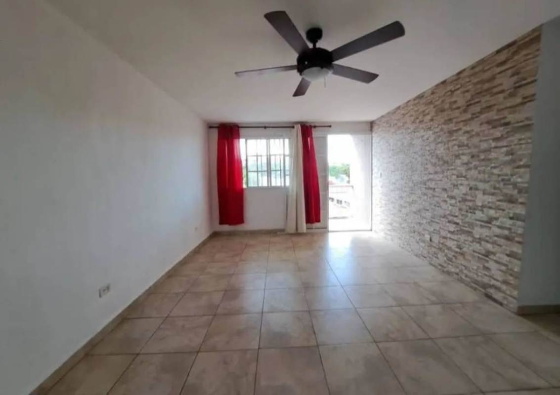 Living room with stone accent wall, ceiling fan and window in Villa Lucre Apartment Panama City