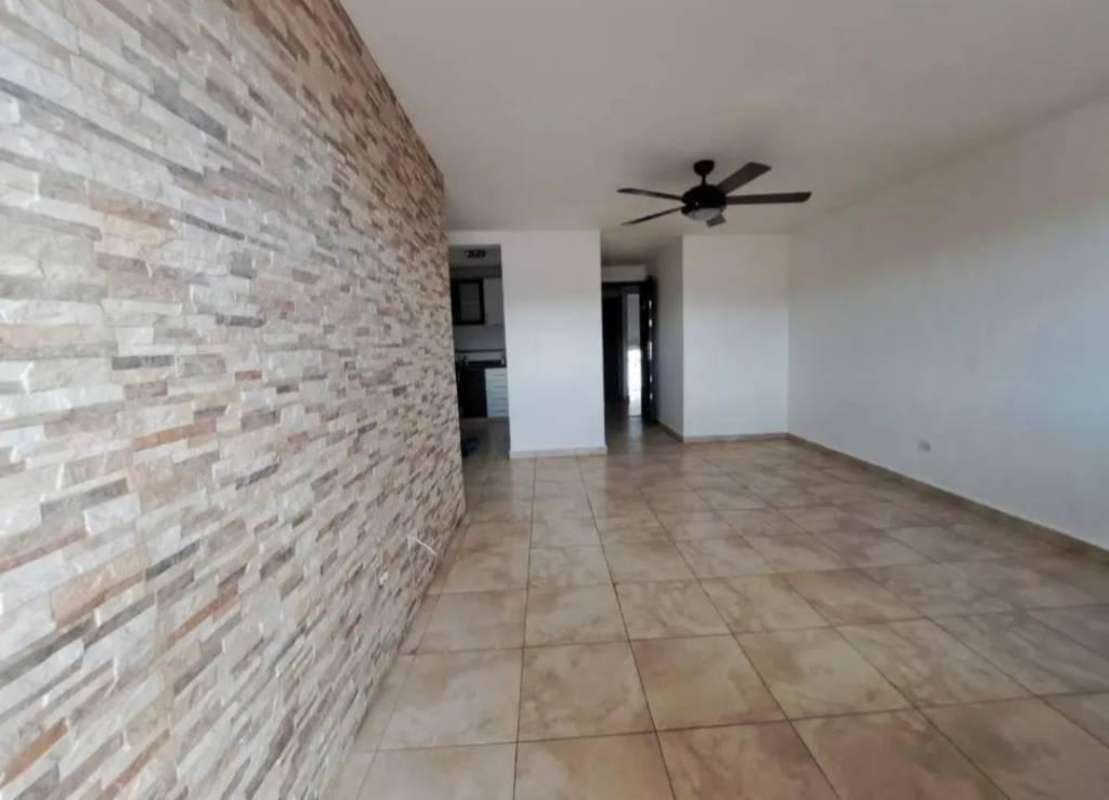 Spacious living room area with tile floor, ceiling fan, and stone accent wall in Panama Villa Lucre