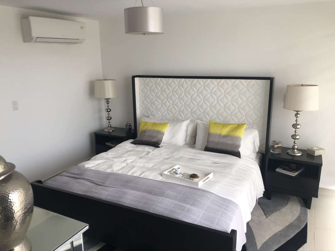 Contemporary master bedroom with designer headboard, AC, nightstands and modern lighting Costa Sur Village Panama