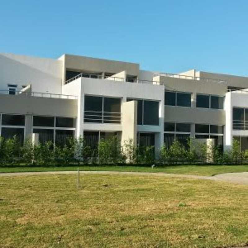 Multi-story residential building with large windows, balconies, green outdoor space in Costa Sur Panama